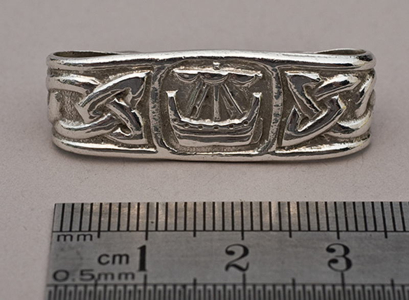 Silver antique old Celtic scarf ring with traditional design border in  sand.. Hand made traditional jewellery concept Stock Photo